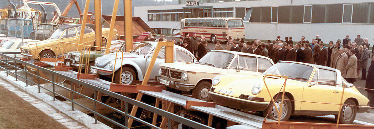 Historische Fahrzeuge auf Parksystemen vor Firmengebäude