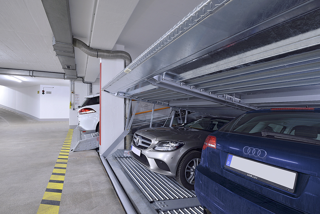 Klaus Multiparking - Referenzobjekt München Eine Tiefgarage mit Parksystemen im Vordergrund, in denen mehrere Autos stehen